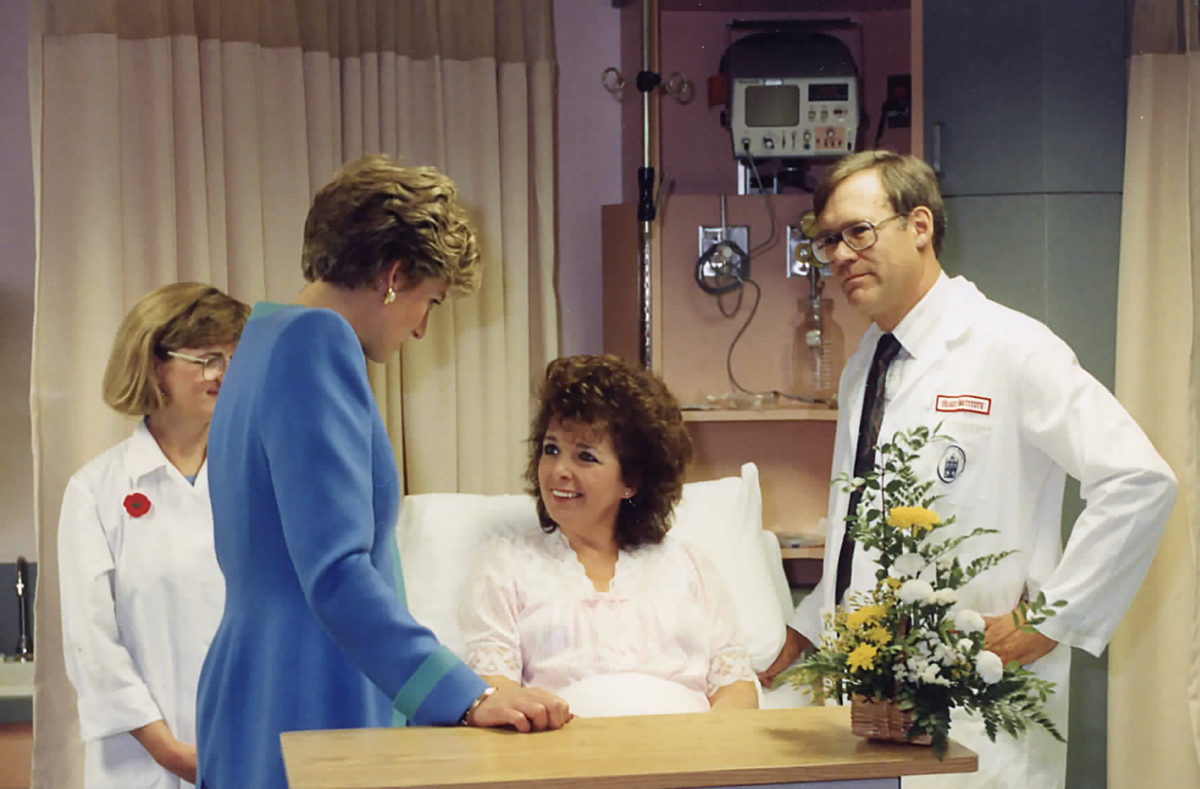 Princess Diana and Dr. James Robblee visit with a patient.